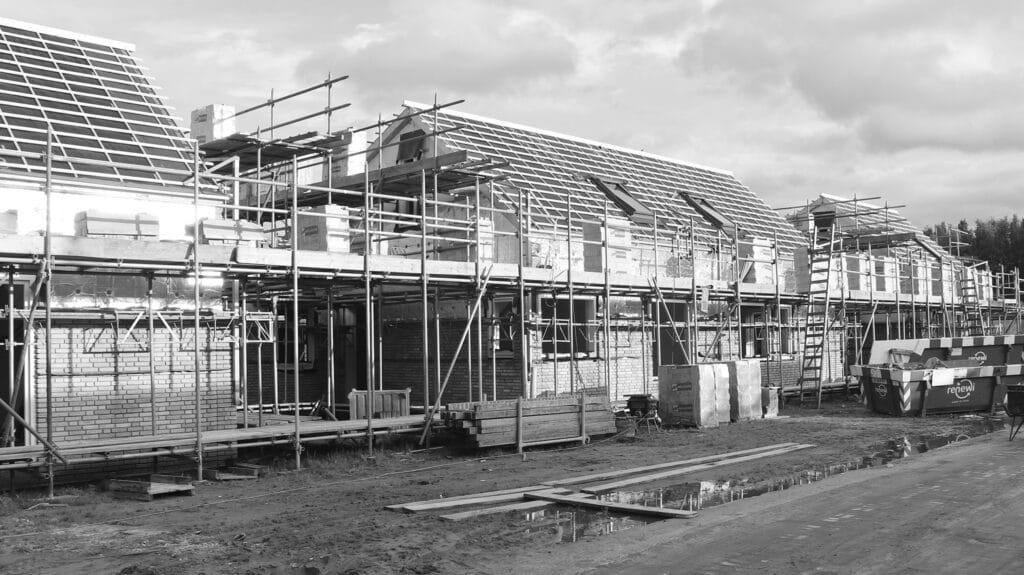 Twee-onder-een-kap in aanbouw: metselwerk halverwege, kozijnen zonder glas, prefab dakplaten met Velux dakramen gereed.
