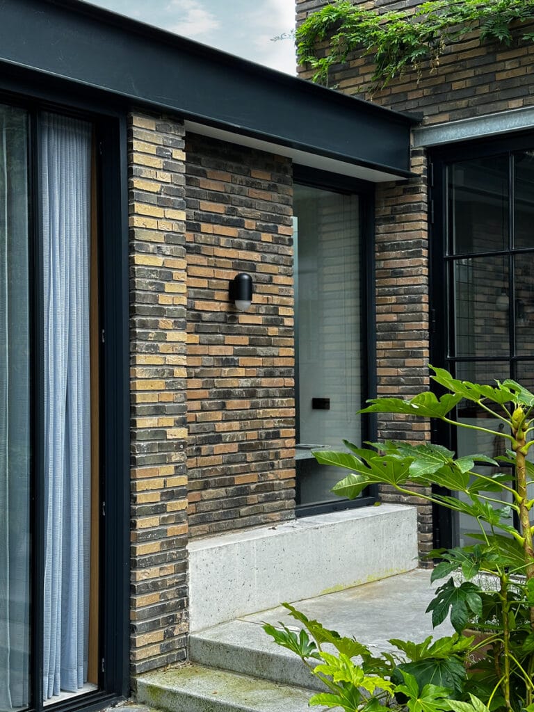 Nieuwe metselwerk penant, raam vervangt loopdeur, betonnen zitelement, stalen UNP ligger dakrand, Schellevis betontreden naar drempelloos terras/tuinkamer.