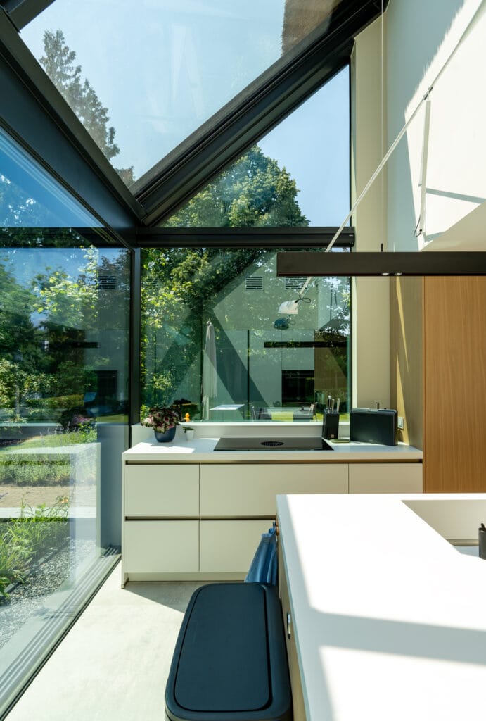 Interieur keuken uitbouw: minimalistische staalconstructie, glas, lessenaarsdak, zicht op rieten kap.