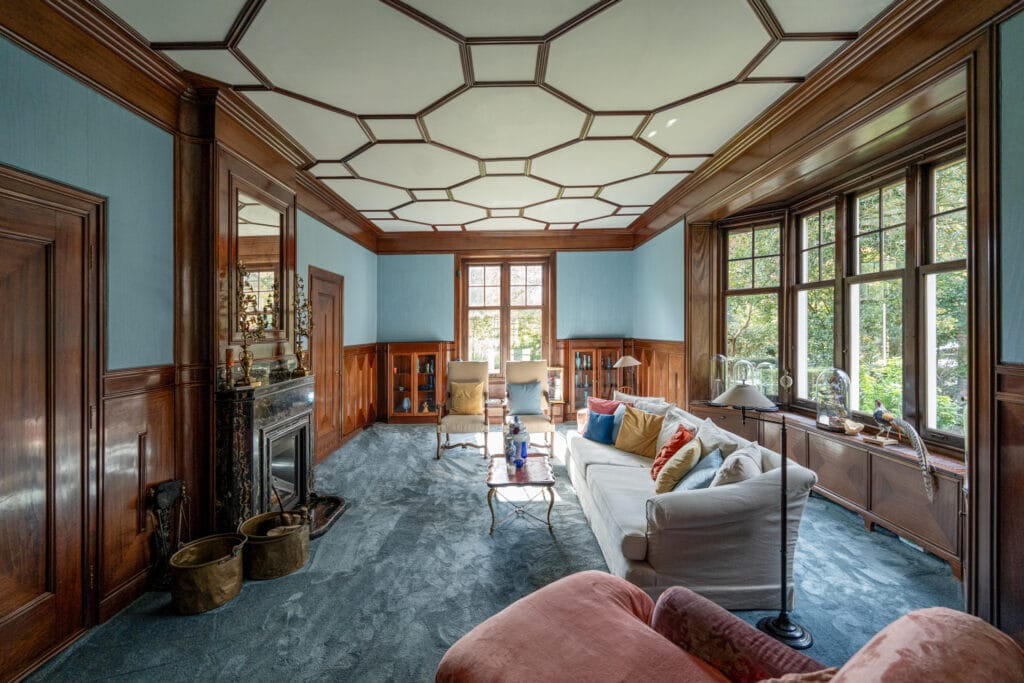 Interieur woonkamer Karel de Bazel: hoogpolig tapijt, stoffen wandbekleding, houten sierlijsten, geometrisch plafond, Portoro marmeren openhaard.